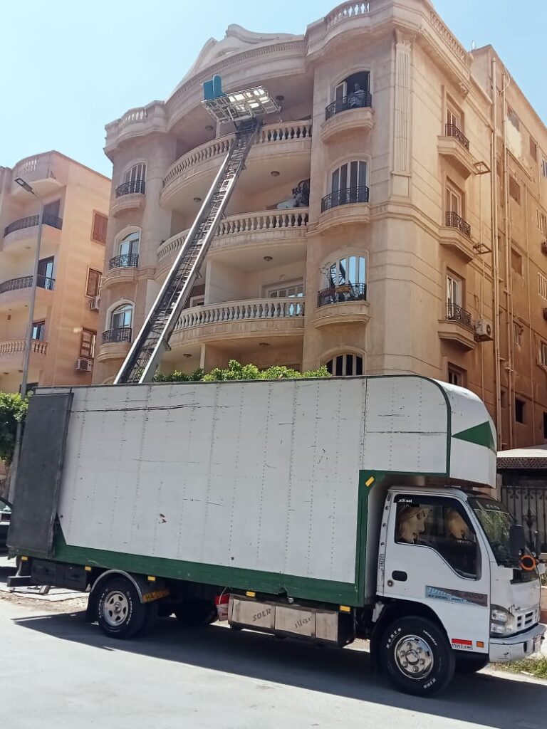 عربية نقل عفش مع ونش رفع أثاث أمام مبنى سكني